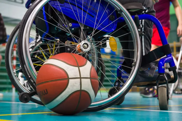 Zdjęcie przedstawia piłkę leżąca przy wózku sportowca z niepełnosprawnością