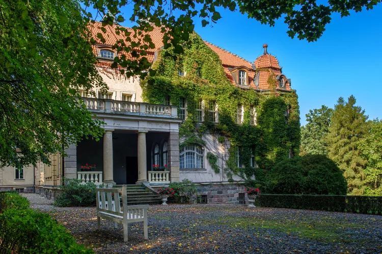 zdjecie przedstawiajace palac w lezanach od zewnatrz z biala laweczka przed budynkiem