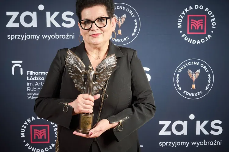 Prof. Ilona Dulisz w czarnym kostiumie trzyma statuetkę 