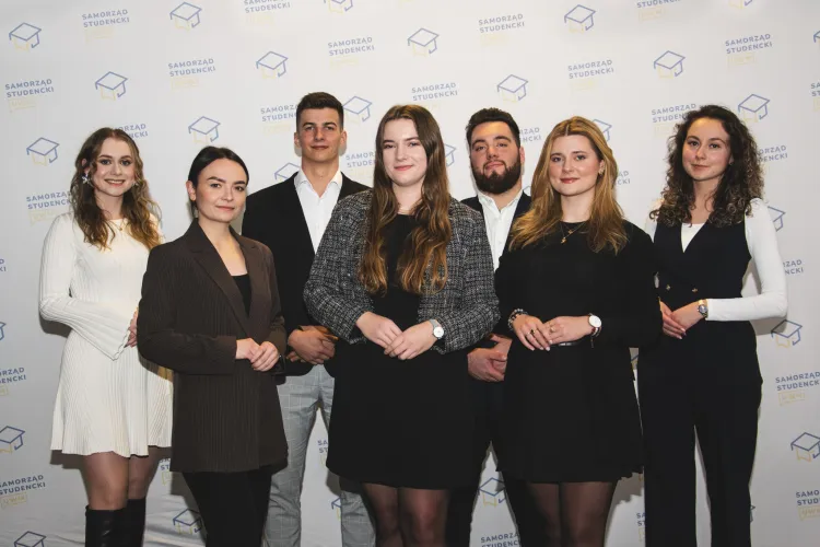 Rada Uczelniana Samorządu Studenckiego - skład prezydium. Siedem osób stoi na tle ścianki z logo RUSS / fot. Archiwum RUSS UWM