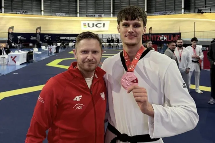 Szymon Piątkowski (po prawej) z medalem na szyi. Obok stoi jego trener