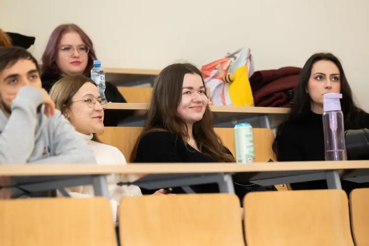 studenci siedzą w ławkach i słuchają wykładu