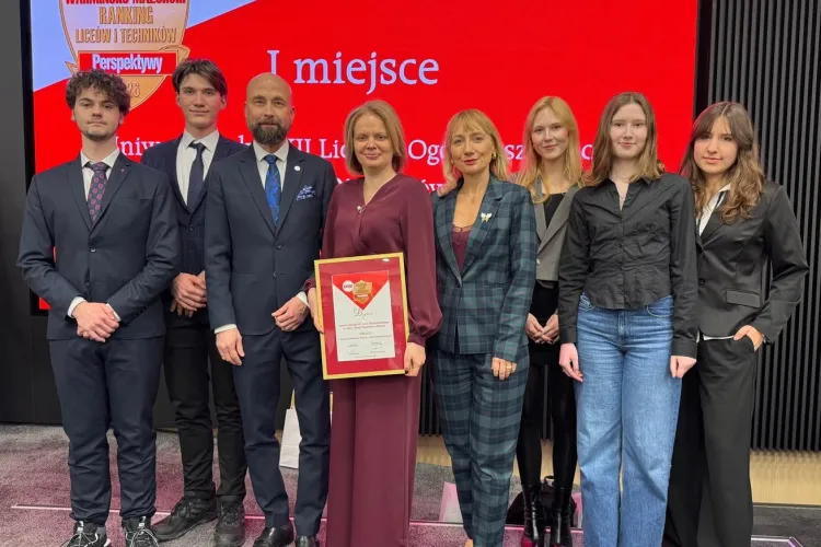 Dyrekcja i uczniowie Uniwersyteckiego XII LO pozują wspólnie z prof. Sławomirem Przybylińskim, prorektorem UWM do zdjęcia. Dyrektorka szkoły Dorota Linkiewicz trzyma w ręku dyplom