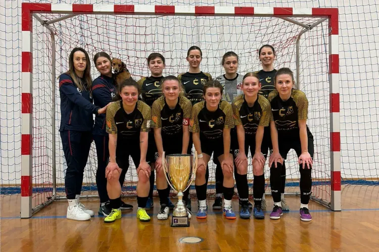 Drużyna AZS UWM High Heels pozuje do zdjęcia z pucharem na tle bramki 