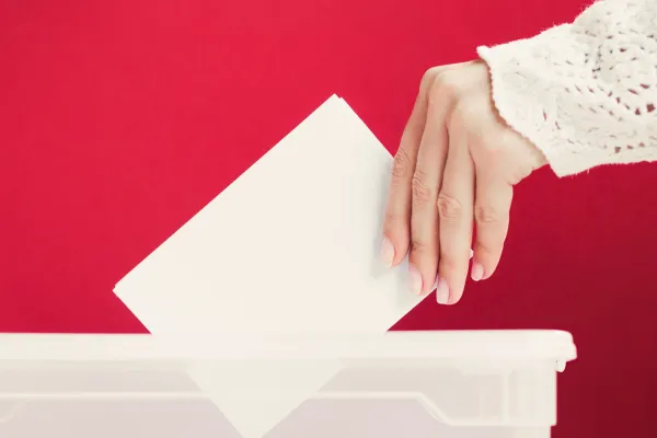 Ręka wkłada kartę głosowania do urny