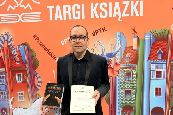 Dr hab. Miłosz Babecki pozuje z książką i dyplomem 