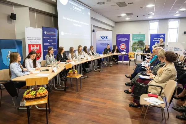 Uczestnicy finału Ogólnopolskiej Olimpiady o Zdrowiu siedzą przy stołach, przed nimi - widownia