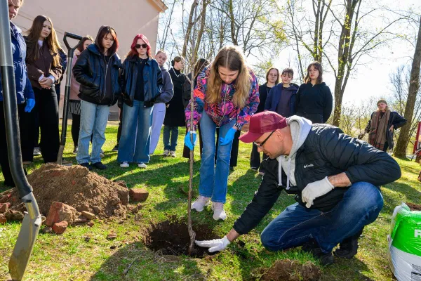 Sadzenie drzewka, obok młodzież