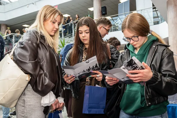 Trzy uczestniczki Targów Pracy przeglądają folder informacyjny