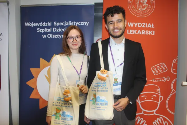 Dwoje studentów pozuje z gadżetami konferencji Scalpellum
