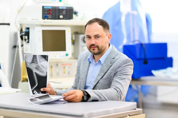 Prof. dr hab. wet. Yauheni Zhalniarovich siedzi przy biurku i trzyma w rękach zdjęcie rentgenowskie