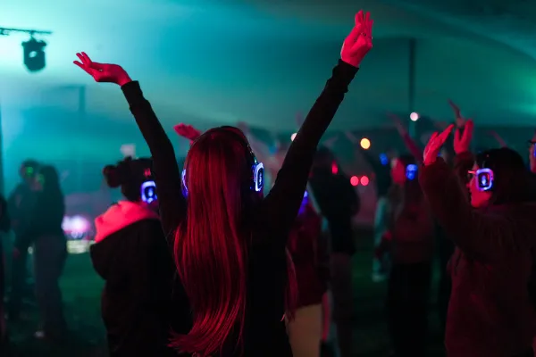 Impreza silent party. Dziewczyna podczas zabawy unosi radośnie obie ręce