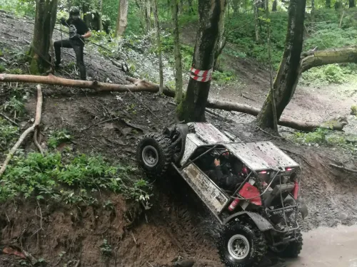 Mężczyzna ciągnie na linie pod górę samochód terenowy